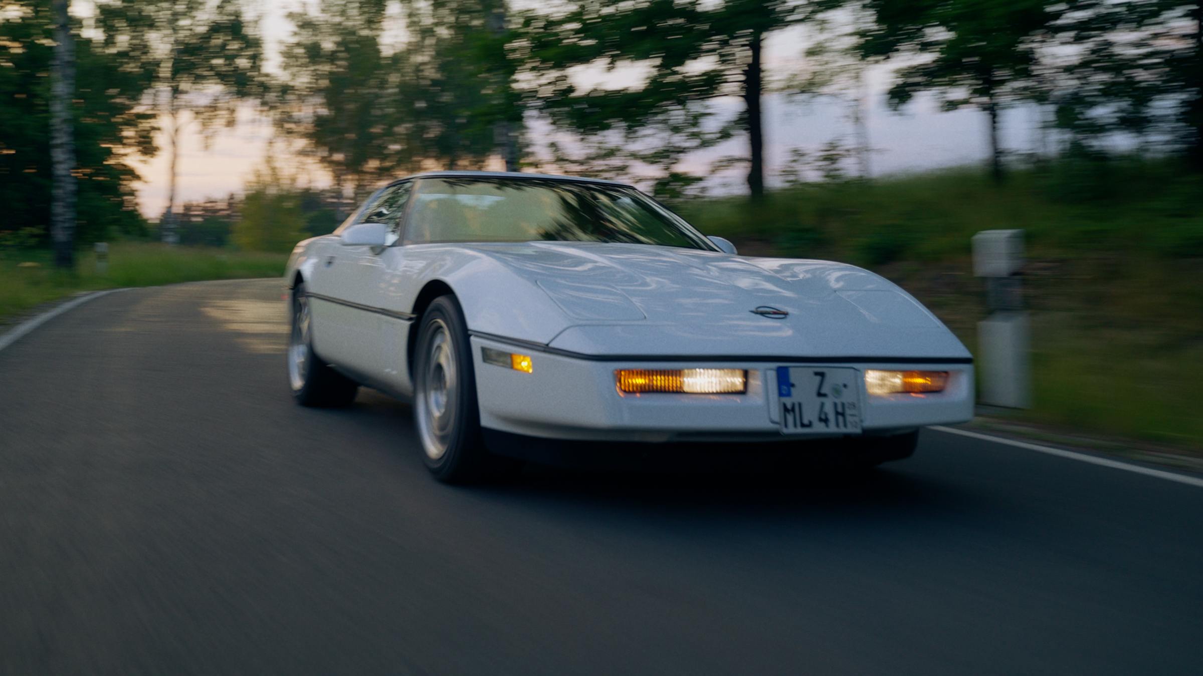Weiße Corvette C4 auf einer Landstraße in der Dämmerung