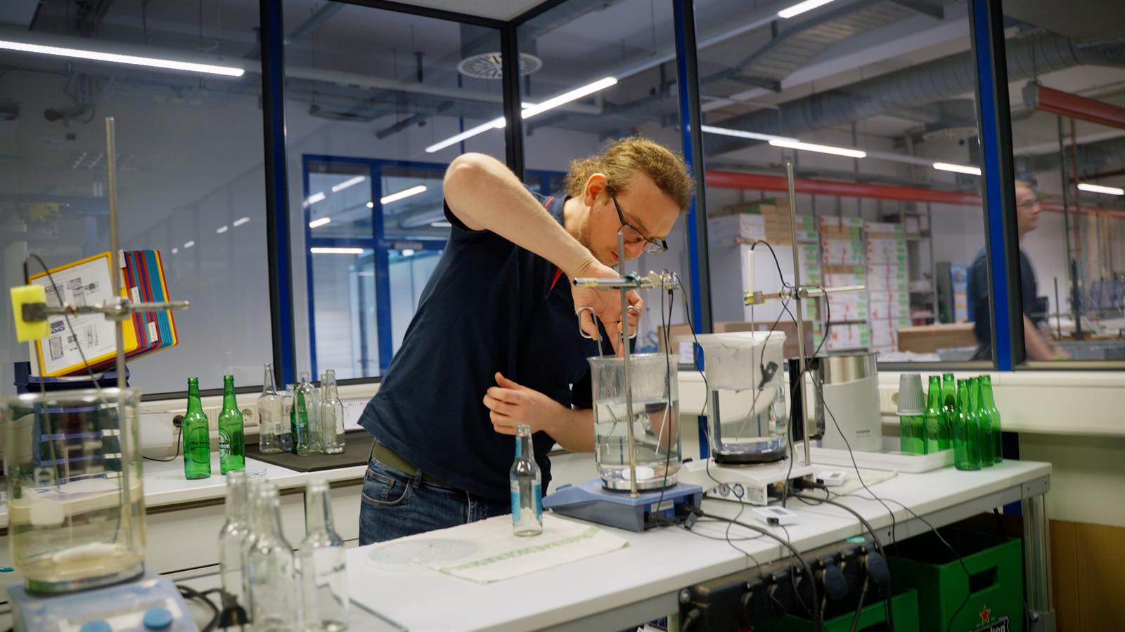 Mitarbeiterin im Labor füllt eine Flüssigkeit in ein Becherglas