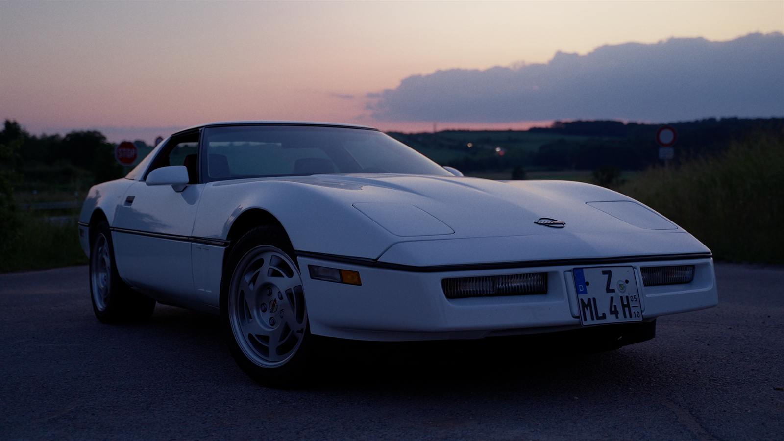 Weiße Corvette C4 in der Abenddämmerung vor dem Sonnenuntergang