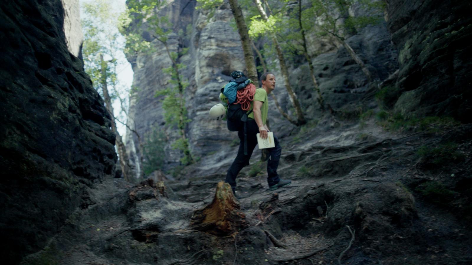 Kletterer mit Rucksack auf dem Zustieg durch eine Felsschlucht